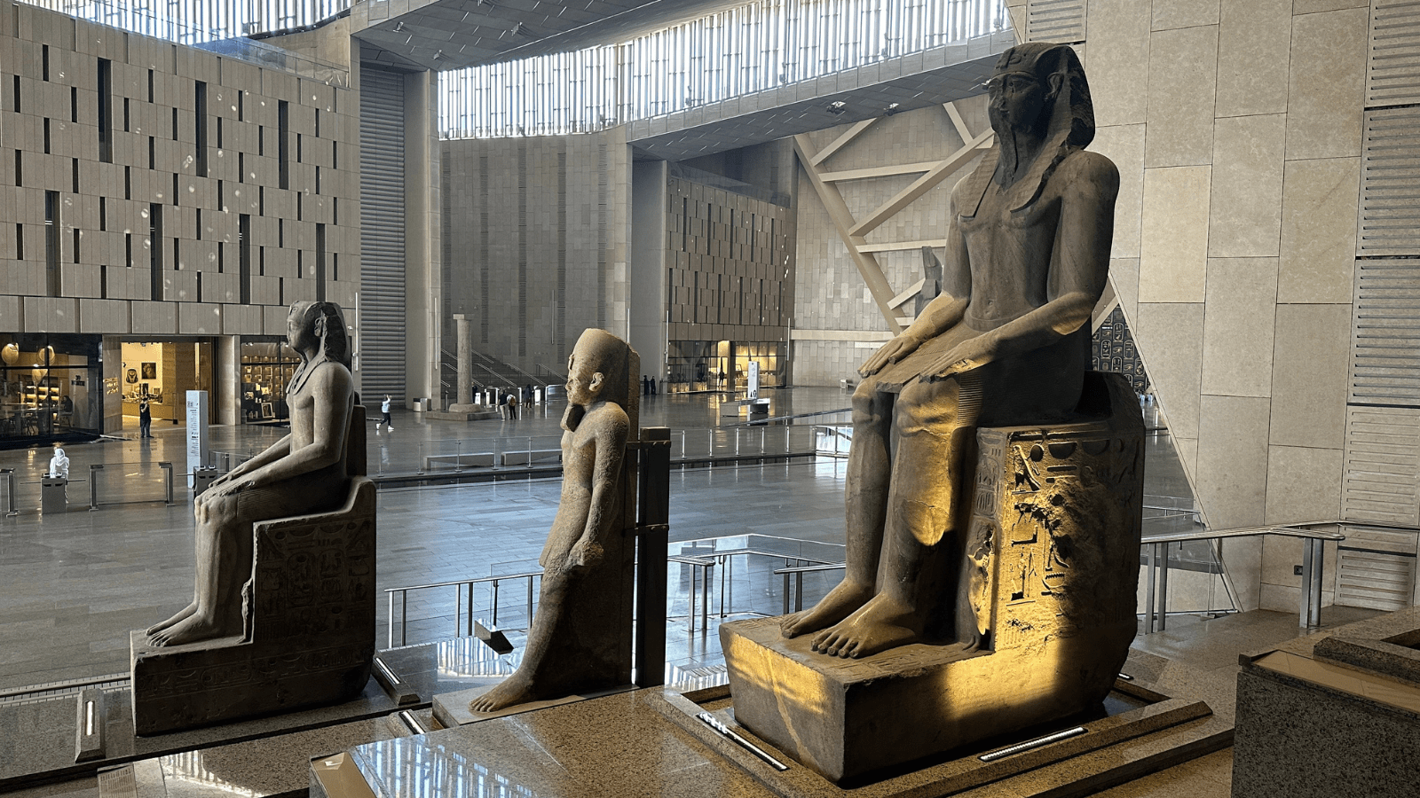 Grand Egyptian Museum galleries with pharaonic seated statues inside the atrium