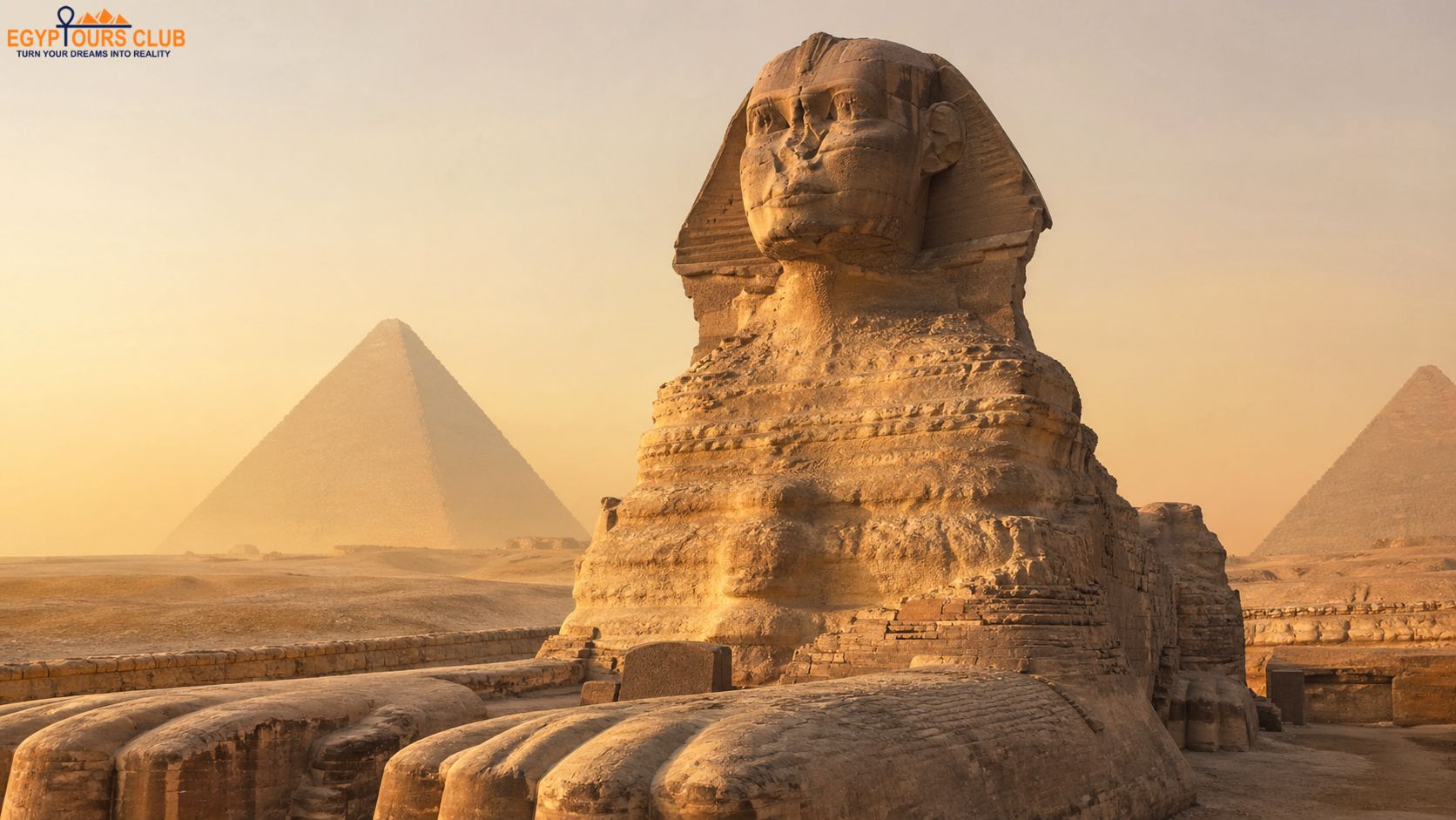 Close-up view of the face of the Great Sphinx of Giza with the pyramids visible behind it